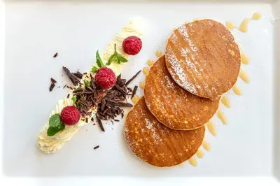 a white plate with two pancakes and strawberries on it at Stadt Hotel Città in Bolzano