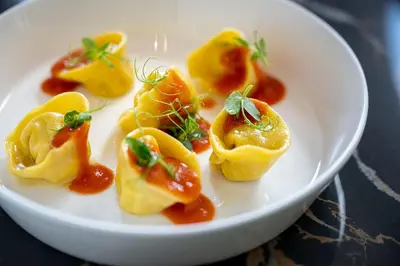 a plate of food with dumplings on a table at Stadt Hotel Città in Bolzano