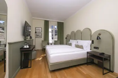 a bedroom with a large white bed and a table at Stadt Hotel Città in Bolzano