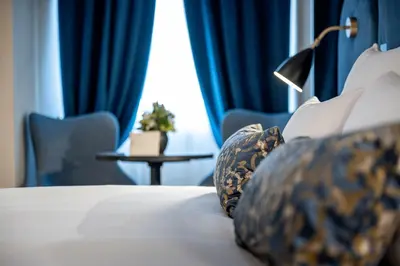 a bedroom with a bed with blue curtains and a table at Stadt Hotel Città in Bolzano
