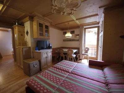 a bedroom with a large bed and a dining room at Appartamento Brentegani in Arabba