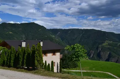 a house on a hill with mountains in the background at Unterkofler Farm Holiday - Peaceful Nature Stay with Stunning Panoramic Views near Bolzano in San Genesio Atesino