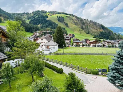 a small village in the mountains with a green field at Ciasa Fam Comploi in San Vigilio Di Marebbe