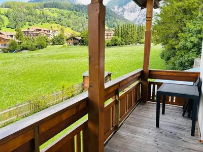 a wooden porch with a view of a green field at Ciasa Fam Comploi in San Vigilio Di Marebbe