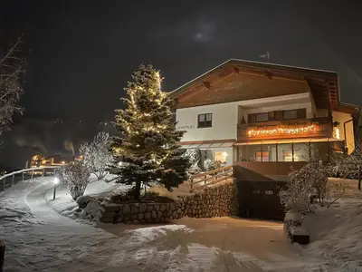 a christmas tree in the snow in front of a house at Ciasa Fam Comploi in San Vigilio Di Marebbe