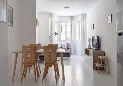 a white living room with a table and chairs at Erker Apartment in Bolzano