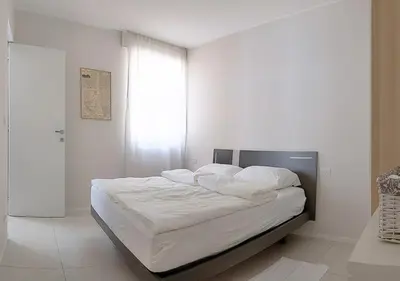 a bedroom with a bed with white sheets and a window at Erker Apartment in Bolzano