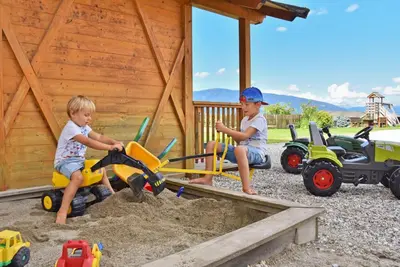 two young boys playing with toys in the sand at Fuchshof in Perca