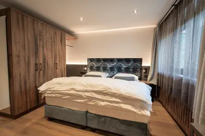 a bedroom with a large bed with two chairs at Villa A - NEW OPENING in Selva di Val Gardena