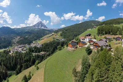 a village on a hill with mountains in the background at Canalhof in Antermoia