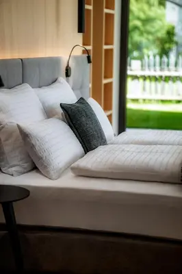 a bed with white pillows on it with a window at Anna Lodges Dolomites in Santa Cristina in Val Gardena