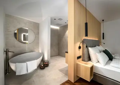a bathroom with a tub and a bed and a mirror at Anna Lodges Dolomites in Santa Cristina in Val Gardena