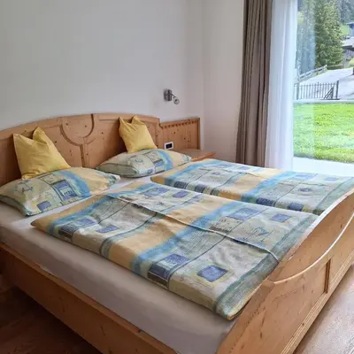 a bedroom with a bed with a wooden frame and a window at Apartment Romana in Selva di Val Gardena
