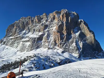 a mountain covered in snow with a person standing in front at Apartment Romana in Selva di Val Gardena