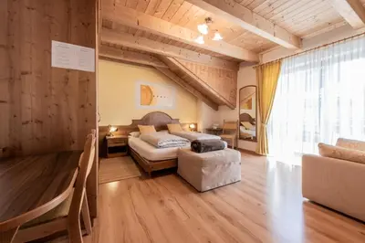 a bedroom with a bed and a chair in a room at Les Gomines BB***** in San Vigilio Di Marebbe