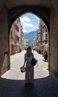 a woman walking through an archway in a street at T-Collection Premium Apartments in Vipiteno