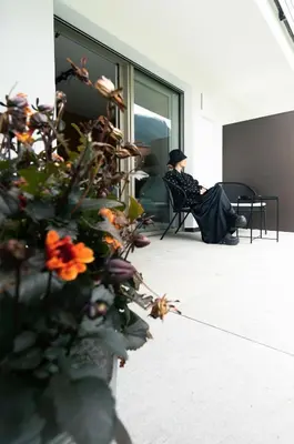 a woman sitting in a chair in a room with a plant at T-Collection Premium Apartments in Vipiteno