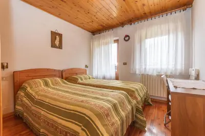 a bedroom with two beds and a wooden ceiling at Casa Morel in Falcade