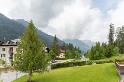 a park with a green lawn in front of a mountain at Casa Morel in Falcade