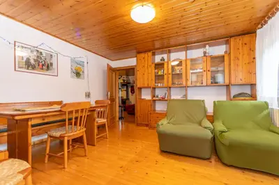 a living room with a table and a green couch at Casa Morel in Falcade