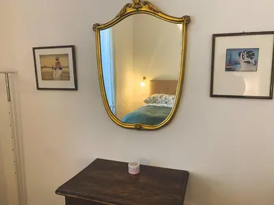 a mirror on a wall with a bed and a table at Palais Carducci in Bolzano