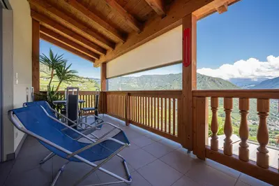 a blue rocking chair on a balcony with a view at Appartement Schusterhof in Gries