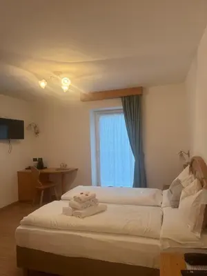 a hotel room with a bed with towels on it at Garnì Villa Elsa in Pozza di Fassa
