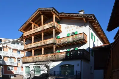 a building with wooden balconies on the side of it at Garnì Villa Elsa in Pozza di Fassa