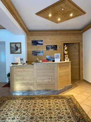 a lobby with a wooden counter and a rug at Garnì Villa Elsa in Pozza di Fassa