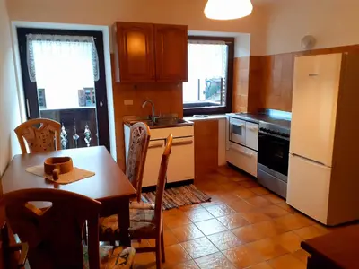 a kitchen with a table and a white refrigerator at Appartamento GIRASOLE in Trodena