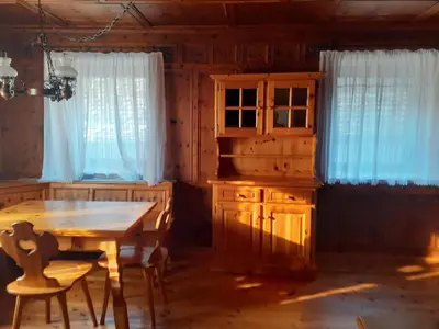 a dining room with a table and a wooden cabinet at Appartamento GIRASOLE in Trodena