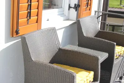 two wicker chairs with a yellow pillow on a porch at Wiesenheim- Unterer Plattenhof 