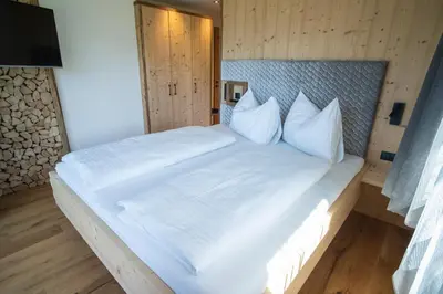 a bedroom with a large bed with white sheets and pillows at Chalet am Wiesenweg in Chiusa