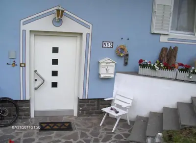 a blue building with a white door and a white chair at villa mahlfertheiner in Castelrotto