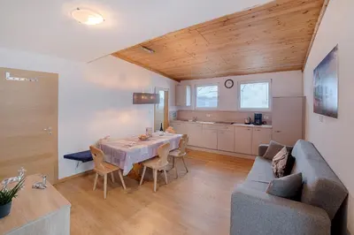 a kitchen and dining room with a table and a couch at Appartements Tirol in San Lorenzo di Sebato