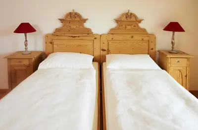 two beds in a bedroom with two lamps on night stands at Weingut Stuck in Appiano sulla Strada del Vino