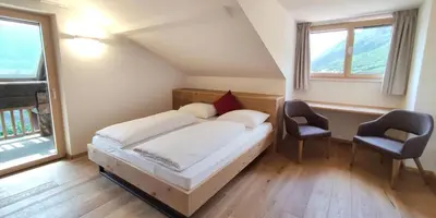 a bedroom with a bed and two chairs in it at Mittelbergerhof Ferienwohnungen in Vilpiano