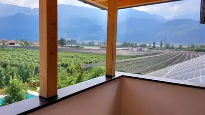 a balcony with a view of a field and mountains at Mittelbergerhof Ferienwohnungen in Vilpiano