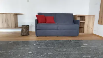 a blue couch with two red pillows in a living room at Mittelbergerhof Ferienwohnungen in Vilpiano