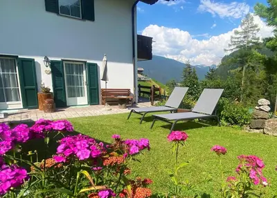 two chairs sitting in a yard with flowers at Alpine Chalet CESA VEDLA -nature & silence in Ortisei