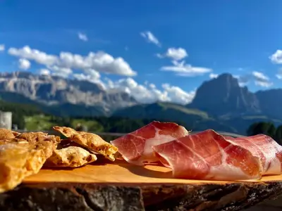 a plate of food with meat and bread on a table at Alpine Chalet CESA VEDLA -nature & silence in Ortisei