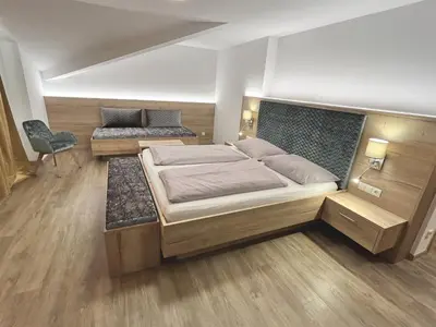 a bedroom with a large bed and a chair at Hotel Sonnenheim in Vipiteno