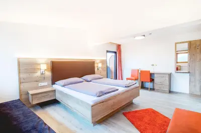 a bedroom with a large bed and a desk at Hotel Sonnenheim in Vipiteno