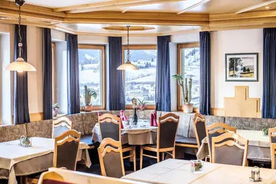 a restaurant with tables and chairs and windows at Hotel Sonnenheim in Vipiteno