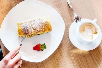 a plate with a piece of cake and a cup of coffee at Hotel Sonnenheim in Vipiteno