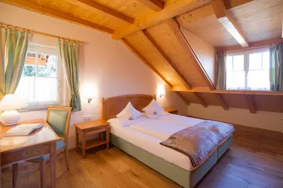 a bedroom with a bed and a desk and windows at Gutshof Sinn in Caldaro