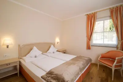 a bedroom with a bed and a chair and a window at Gutshof Sinn in Caldaro