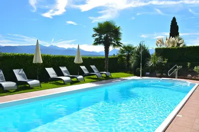 a swimming pool with lounge chairs and umbrellas at Gutshof Sinn in Caldaro