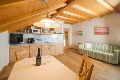a kitchen and living room with a table with a bottle of wine at Gutshof Sinn in Caldaro