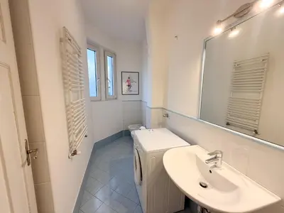 a white bathroom with a sink and a mirror at Cozy city center apartment in Bolzano